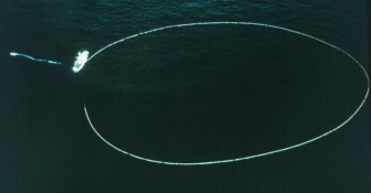 1. Positioned in the Pacific Ocean the seine, a large fishing net used in the purse seine fishing technique, is almost a perfect circle. The purse seiner, the ship attached to the net, is starting to pull the net back on board. The workboat (far left) secured to the purse seiner, is now acting like a tugboat, pulling the purse seiner away from the net so that it does not become entangled. Photo Credit: Courtesy of South Pacific Commission (SPC). This photograph is included in the National Oceanic and Atmospheric Administration Photo Library (http://www.photolib.noaa.gov), Fisheries Collection, National Oceanic and Atmospheric Administration (NOAA, http://www.noaa.gov), United States Department of Commerce (http://www.commerce.gov), Government of the United States of America.