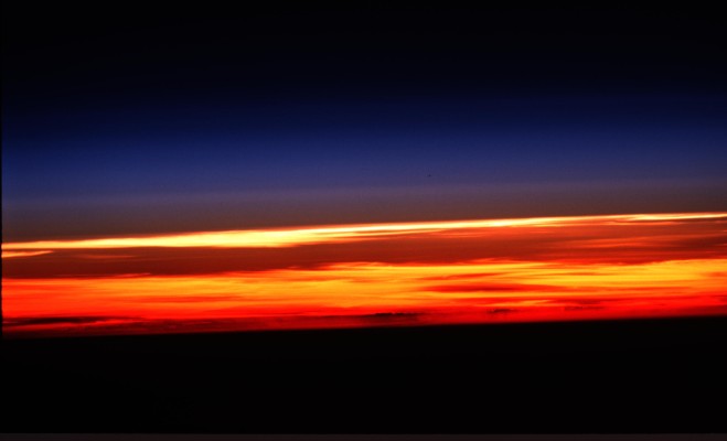 The Blackness of Outer Space Above, the Center Blue Envelope of Gases, Know as the Limb, at a Luminous and Colorful Sunset, Protecting Our Home, the Earth, Below. Photo Credit: Earth's Atmospheric Limb at Sunset. Sciences and Image Analysis, NASA-Johnson Space Center. 8 December 2003. 'Astronaut Photography of Earth - Quick View.' <http://eol.jsc.nasa.gov/scripts/sseop/photo.pl?mission=ISS001&roll=421&frame=24>; National Aeronautics and Space Administration (NASA, http://www.nasa.gov), Government of the United States of America (USA).
