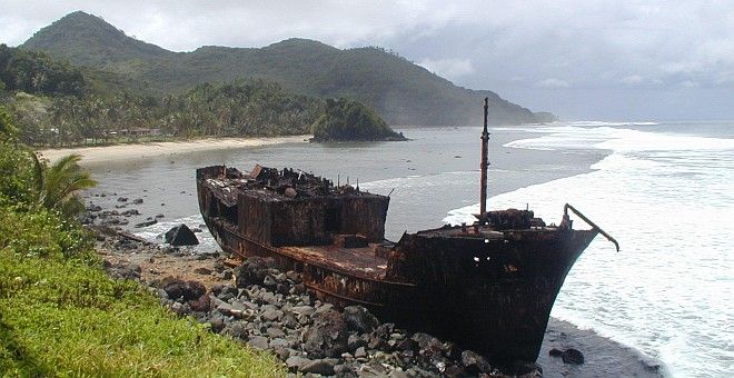 A Rusted and Broken Ship Thrown Ashore in American Somoa (USA). Photo Credit: "American Samoa Observatory, Trip to Tula", Samoa Observatory Cape Matatula, American Samoa (http://www.cmdl.noaa.gov/obop/smo), Climate Monitoring and Diagnostics Laboratory (http://www.cmdl.noaa.gov), National Oceanic and Atmospheric Administration (NOAA, http://www.noaa.gov), United States Department of Commerce (http://www.commerce.gov), Government of the United States of America (USA).