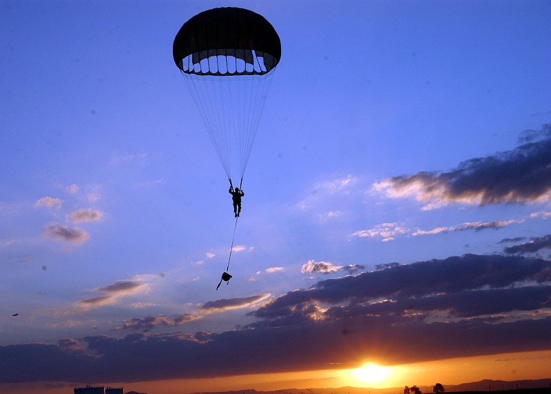 With the Parachute Fully Deployed, a Parachuter With Explosive Ordnance Mobile Unit Eight (EODMU-8) Floats Down to Earth Out of the Blue Sky at Sunrise or Sunset, August 28, 2006. Sigonella, Sicily, Repubblica Italiana - Italian Republic (Italy). Photo Credit: Mass Communication Specialist Seaman Chad Zenthoefer, Navy NewsStand - Eye on the Fleet Photo Gallery (http://www.news.navy.mil/view_photos.asp, 060828-N-3572Z-025), United States Navy (USN, http://www.navy.mil), United States Department of Defense (DoD, http://www.DefenseLink.mil or http://www.dod.gov), Government of the United States of America (USA).