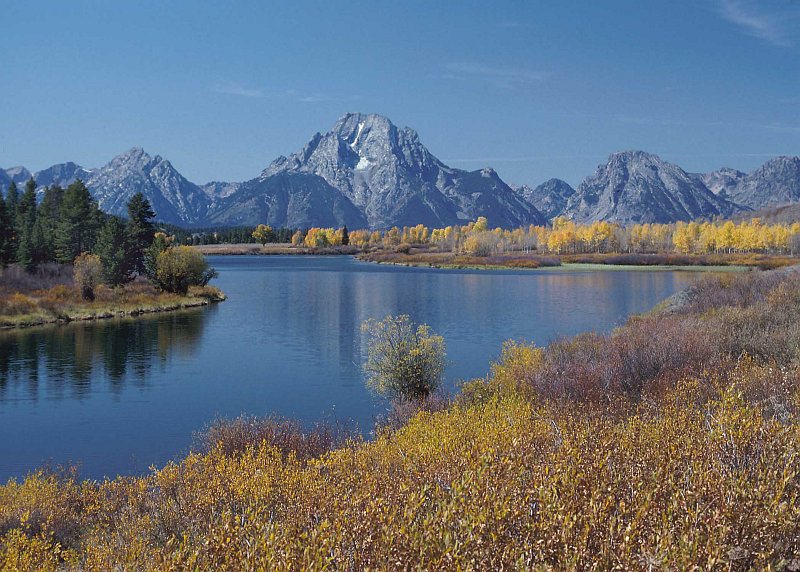 Scenic View of Mountain Peaks, Trees In Autumn (Fall Season) Colors, Evergreen Trees, and the Snake River Outside Jackson, State of Wyoming, USA. Photo Credit: Tim McCabe (1992, http://photogallery.nrcs.usda.gov, NRCSWY92004), USDA Natural Resources Conservation Service (NRCS, http://www.nrcs.usda.gov), United States Department of Agriculture (USDA, http://www.usda.gov), Government of the United States of America (USA).