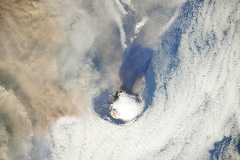 1. Sarychev Peak Volcano Erupts -- Clearing,  Possibly From Its Shock Wave, A Circle In the Cloud Deck Above -- With A Plume of Brown Ash and Steam, June 12, 2009 at 22:15:25 GMT, Matua Island, Kuril Islands, Rossiyskaya Federatsiya -- Russian Federation, As Seen From the International Space Station (Expedition 20) Photo Credit: NASA, International Space Station (Expedition Twenty); ISS020-E-8737, Sarychev Peak, Invisible shock wave, Volcanic plume, Matua Island, Kuril (or Kurile) Islands; Image Science and Analysis Laboratory, NASA-Johnson Space Center. 'Astronaut Photography of Earth - Display Record.' <http://eol.jsc.nasa.gov/scripts/sseop/photo.pl?mission=ISS020&roll=E&frame=8737>; National Aeronautics and Space Administration (NASA, http://www.nasa.gov), Government of the United States of America (USA).