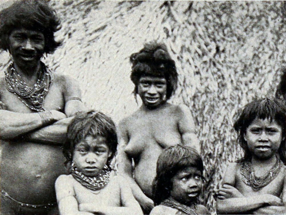 A photograph of a native family consisting of a man, woman, and three children. All are wearing loinclothes, and the man and the boys have their arms crossed in front of them.