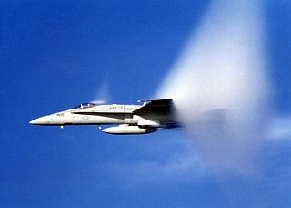 8. An F-18 Hornet From Strike Fighter Squadron 137 (VFA-137), United States Navy, Off the Coast of San Diego, California, USA, Pacific Ocean. Reaching the sound barrier, breaking the sound barrier: Flying at transonic speeds (flying transonically) -- speeds varying near and at the speed of sound (supersonic) -- can generate impressive condensation clouds caused by the Prandtl-Glauert Singularity. For a scientific explanation, see Professor M. S. Cramer's Gallery of Fluid Mechanics, Prandtl-Glauert Singularity at <http://www.GalleryOfFluidMechanics.com/conden/pg_sing.htm>; and Foundations of Fluid Mechanics, Navier-Stokes Equations Potential Flows: Prandtl-Glauert Similarity Laws at <http://www.Navier-Stokes.net/nspfsim.htm>. Photo Credit: Defense Visual Information Center (DVIC, http://www.DoDMedia.osd.mil, DNSD9905858) and United States Navy (USN, http://www.navy.mil), United States Department of Defense (DoD, http://www.DefenseLink.mil or http://www.dod.gov), Government of the United States of America (USA).