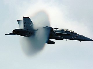 12. An F/A-18F Super Hornet Fighter Assigned to the 'Diamondbacks' of Strike Fighter Squadron One Zero Two (VFA-102). July 27, 2005, USS Kitty Hawk (CV 63), United States Navy in the Philippine Sea. Reaching the sound barrier, breaking the sound barrier: Flying at transonic speeds (flying transonically) -- speeds varying near and at the speed of sound (supersonic) -- can generate impressive condensation clouds caused by the Prandtl-Glauert Singularity. For a scientific explanation, see Professor M. S. Cramer's Gallery of Fluid Mechanics, Prandtl-Glauert Singularity at <http://www.GalleryOfFluidMechanics.com/conden/pg_sing.htm>; and Foundations of Fluid Mechanics, Navier-Stokes Equations Potential Flows: Prandtl-Glauert Similarity Laws at <http://www.Navier-Stokes.net/nspfsim.htm>. Photo Credit: Photographer's Mate 3rd Class Jonathan Chandler, Navy NewsStand - Eye on the Fleet Photo Gallery (http://www.news.navy.mil/view_photos.asp, 050727-N-3488C-051), United States Navy (USN, http://www.navy.mil), United States Department of Defense (DoD, http://www.DefenseLink.mil or http://www.dod.gov), Government of the United States of America (USA).