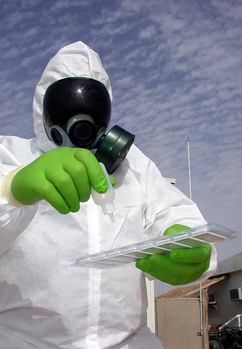 On Guard for Death and Disease in the Air: Dressed in Protective Clothing With a Biological or Chemical Agent Testing Kit in Southwest Asia. Photo Credit: Master Sgt. Michael A. Ward, Air Force Link - Week in Photos, February 25, 2005 (http://www.af.mil/weekinphotos/050225-08.html, "Not your old disaster prepardeness anymore"), United States Air Force (USAF, http://www.af.mil), United States Department of Defense (DoD, http://www.DefenseLink.mil or http://www.dod.gov), Government of the United States of America (USA).