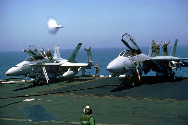 14. A Transonic U.S. Navy F-14A Tomcat Fighter Jet Assigned to Fighter Squadron 102 (VF-102) Conducts A High-Speed Flyby Near the U.S. Navy Aircraft Carrier USS America (CV-66), March 1, 1991, Red Sea. Photo Credit: LCDR Ken Neubauer, United States Navy; Defense Visual Information (DVI, http://www.DefenseImagery.mil, DN-SC-92-02756) and United States Navy (USN, http://www.af.mil), United States Department of Defense (DoD, http://www.DefenseLink.mil or http://www.dod.gov), Government of the United States of America (USA).