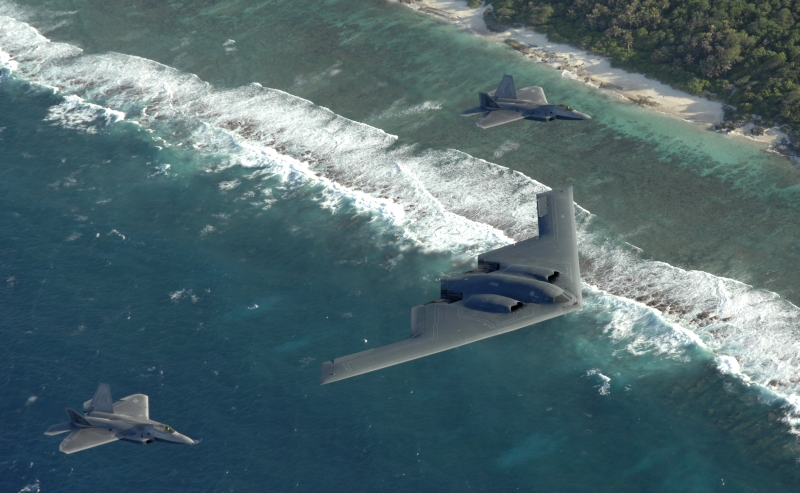6. With the Sandy Coastline In View, Two F-22A Raptor Fighter Jets and One B-2 Spirit Stealth Bomber Fly In Formation Over the Pacific Ocean, April 7, 2009, Territory of Guam, USA. Photo Credit: Master Sgt. Kevin J. Gruenwald, United States Air Force; Defense Visual Information (DVI, http://www.DefenseImagery.mil, 090414-F-6911G-003) and United States Air Force (USAF, http://www.af.mil), United States Department of Defense (DoD, http://www.DefenseLink.mil or http://www.dod.gov), Government of the United States of America (USA).