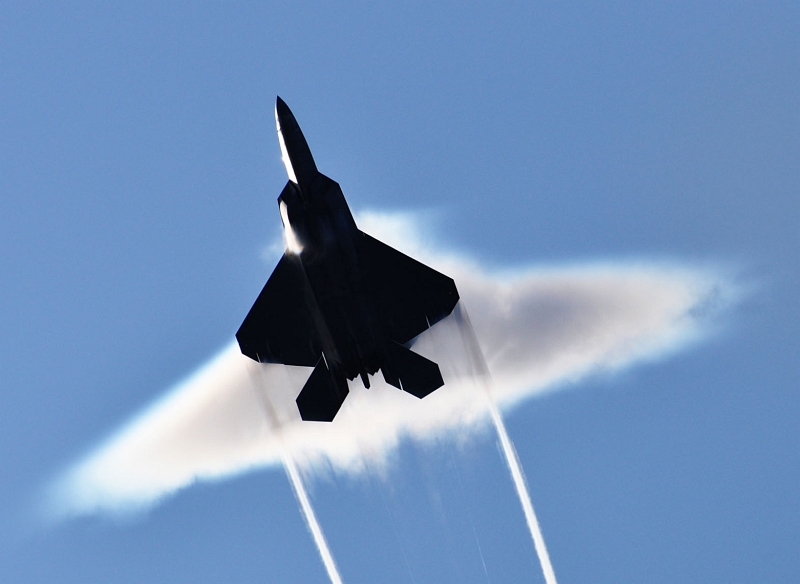 2. Condensation Cloud and Wingtip, or Trailing, Vortices: A United States Air Force F-22A Raptor Stealth Fighter Jet, June 22, 2009, High-Speed Flyby Above the United States Navy Nimitz-Class Aircraft Carrier USS John C. Stennis (CVN 74) During Northern Edge 2009 in the Gulf of Alaska, State of Alaska, USA. Photo Credit: Sonar Technician 1st Class Ronald Dejarnett, United States Navy; Defense Visual Information (DVI, http://www.DefenseImagery.mil, 090622-N-8290D-008) and United States Navy (USN, http://www.navy.mil), United States Department of Defense (DoD, http://www.DefenseLink.mil or http://www.dod.gov), Government of the United States of America (USA).