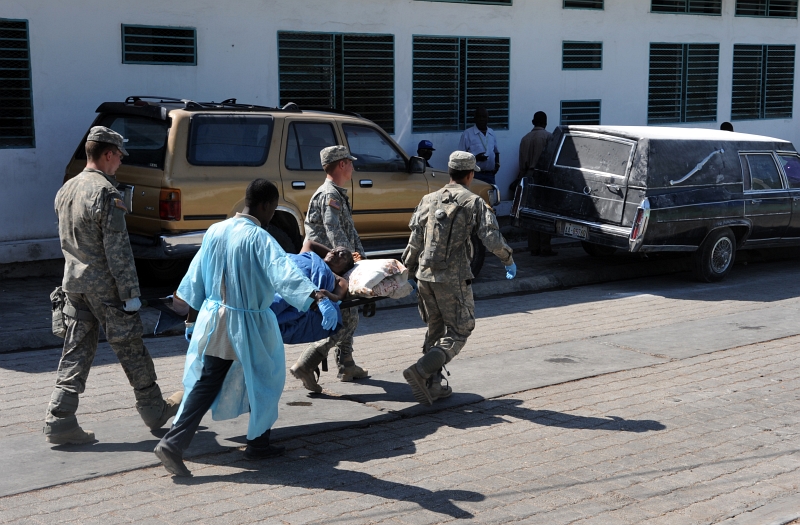42. Four Men -- Three United States Soldiers and One Man Wearing A Blue Hospital Gown -- Move A Stretcher-Bound Patient To A Medical Care Unit At A Hospital In Port-au-Prince, January 22, 2010, Republique d'Haiti (Repiblik d' Ayiti) - Republic of Haiti. Photo Credit: Technical Sgt. Prentice Colter (TSgt), United States Air Force; Defense Visual Information (DVI, http://www.DefenseImagery.mil, 100122-F-7951C-037) and United States Air Force (USAF, http://www.af.mil), United States Department of Defense (DoD, http://www.DefenseLink.mil or http://www.dod.gov), Government of the United States of America (USA).