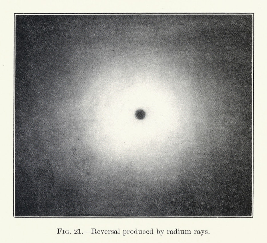 An image of a small pinpoint of black surrounded by white demonstrating “photographic reversal” through prolonged exposure to radium