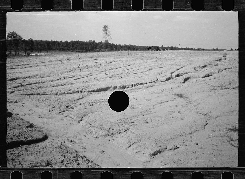 black and white photo of a dry field with a black hole in the centre